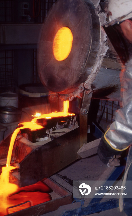 Large bucket of molten gold being poured into ingot molds