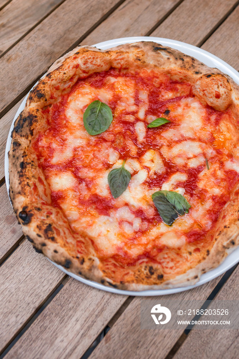 Original neapolitan pizza margherita on wooden table, served in Naples restaurant, Italy