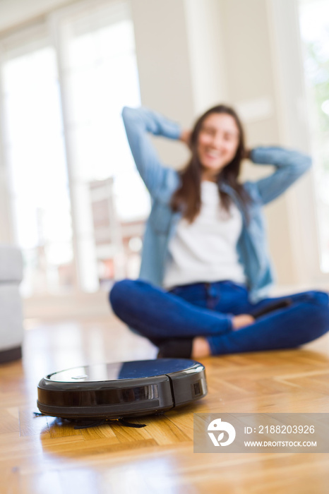 Young woman using automatic vacuum cleaner to clean the floor, controling machine housework robot