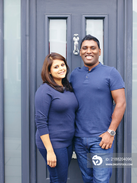 Portrait of smiling couple standing at front door