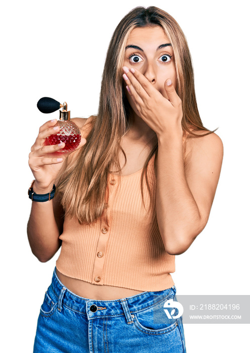 Hispanic young woman holding perfume covering mouth with hand, shocked and afraid for mistake. surprised expression