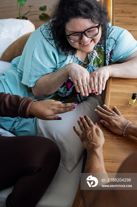 Three friends painting their nails together at home