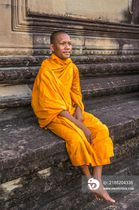 Young Buddhist monk sitting at temple in Angkor Wat, Siem Reap, Cambodia