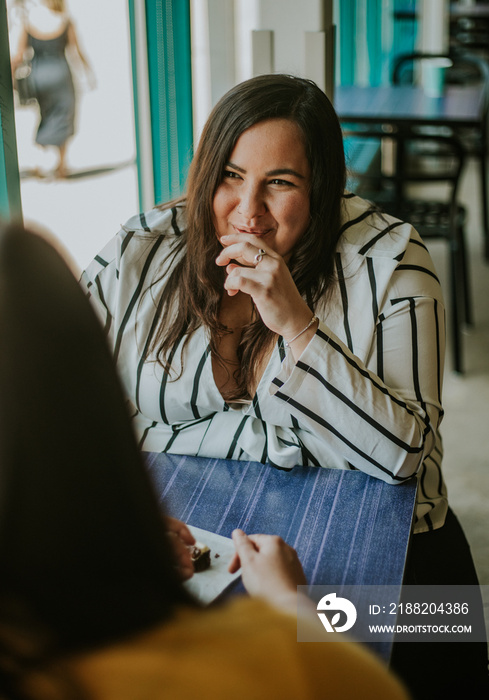 plus size woman smiles and covers mouth when eating