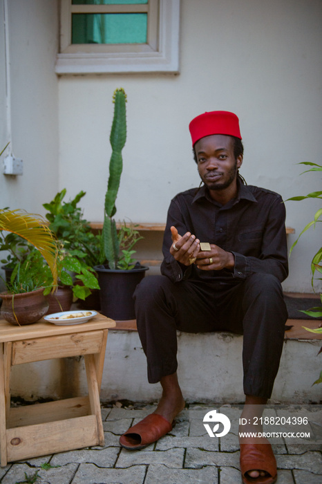 an igbo man sitting outside his house