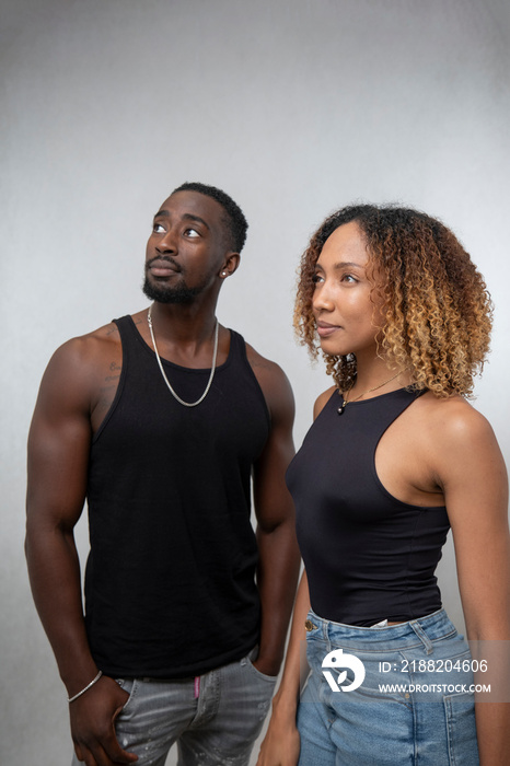 Couple wearing tank tops and looking away