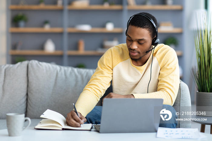 Black guy attending online training from home, taking notes