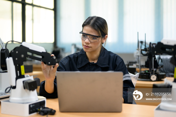 Female technician engineer using laptop checking and operating automatic robotic machine at industrial factory, Worker working with robotic system in factory