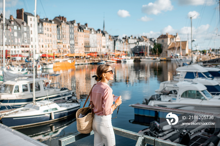 Young woman tourist enjoying beautiful view on the harbour traveling in Honfleur town in Normandy, France