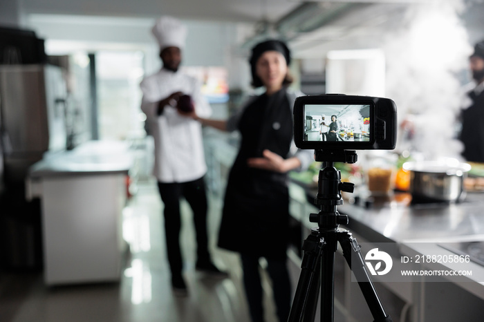 Close up of camera recording food industry workers preparing delicious gourmet dish while broadcasting. Chefs in restaurant professional kitchen filming cooking session for culinary school.