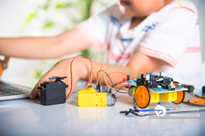 Asian kid boy learns coding and programming with laptop for Arduino robot car, Little child students typing code in computer with car toy, STEAM education AI technology course school learning