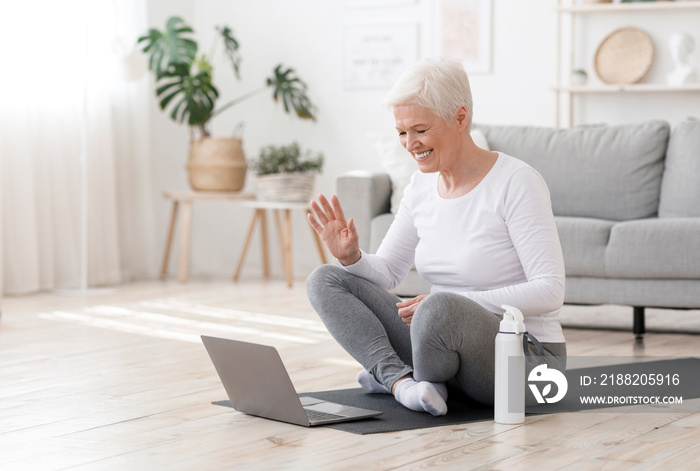 Smiling Senior Woman Training At Home Online Via Laptop, Waving At Camera