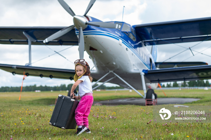 A cute little girl playing on the field by a four-seater private jet dreaming of becoming a pilot