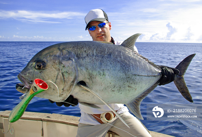 Deep sea fishing, catch of fish, big game fishing, boat fishing, lure fishing, sea fishing. Fisherman holding a big Trevally jack.