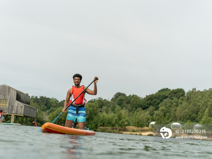 Young man paddleboarding on lake