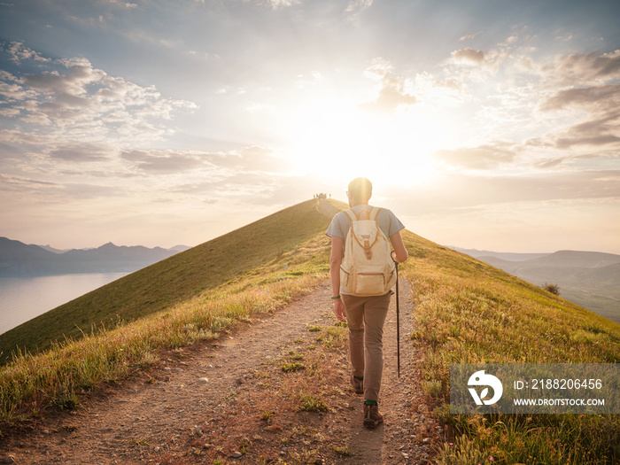 Young man travels alone walking on trail and enjoying on view of mountains and sea landscape at sunset , the lifestyle concept of traveling outdoors.