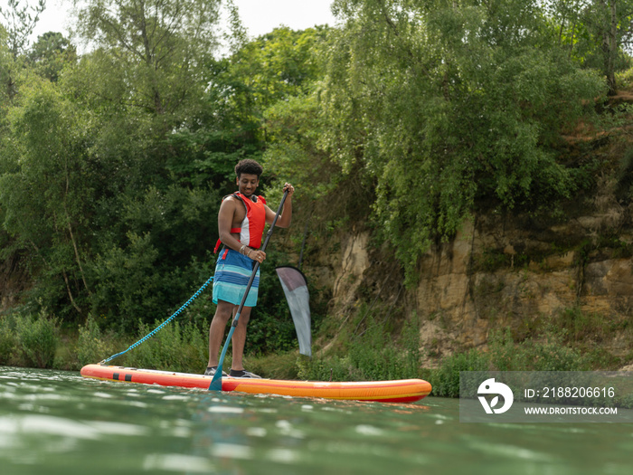 Young man paddleboarding on lake