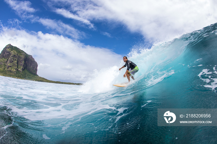 Surfing on big waves against the backdrop of picturesque mountains and beautiful clouds