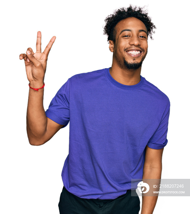 Young african american man with beard wearing casual purple t shirt smiling with happy face winking at the camera doing victory sign. number two.