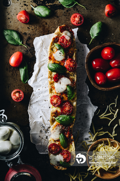 Baked baguette with chees, cherry tomatoes, basil, and mozzarella