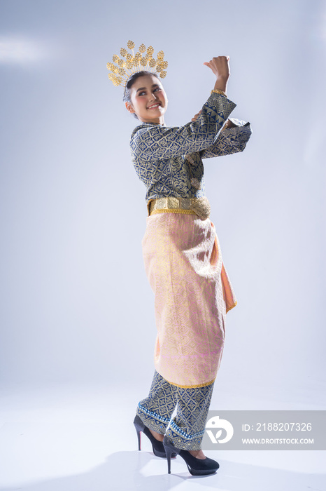 A beautiful Malaysian traditional female dancer performing a cultural dance routine in a traditional outfit on a stage. Full length portrait.