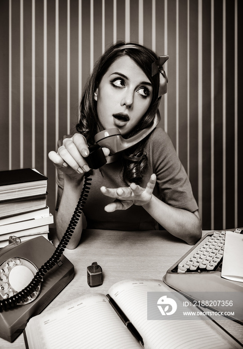 young woman as secretary at her desk near the typewriter and dial phone. 60-s style. Image in black and white color style