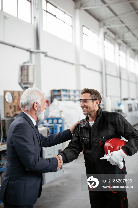 Colleagues working together. Arhitect and worker handshake in factory.