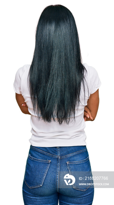 Beautiful hispanic woman wearing casual white tshirt standing backwards looking away with crossed arms