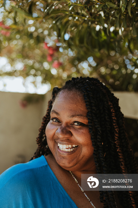 plus size Afro Latinx Haitian American woman smiling under flowering tree looking at camera