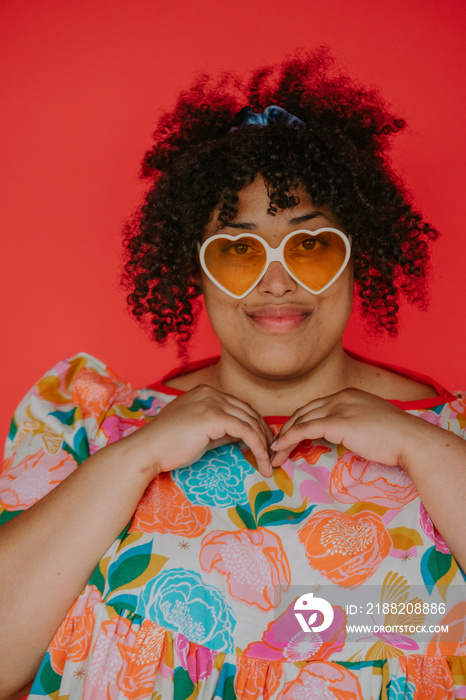 closeup of a plus size person wearing heart sunglasses looking at camera