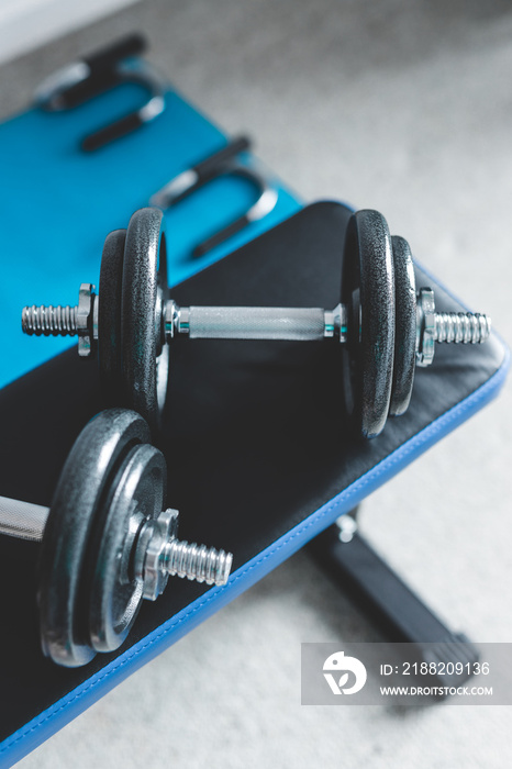 home gym concept, room with dumbbells on gym bench and push-up handles on yoga mat to workout from home