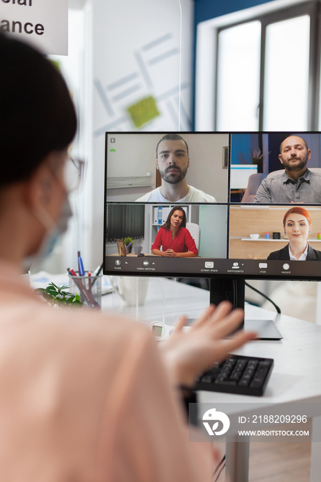 Executive manager with medical face mask discussing management statistics with remote team having online videocall meeting conference on laptop working in startup office. Teleconference on screen