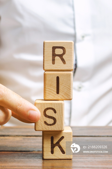 Man removes blocks with the word Risk. The concept of reducing possible risks. Insurance, stability support. Legal protection of business interests. Favorable investment climate. Financial pillow.