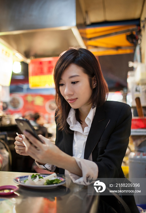 Businesswoman using cellular phone, night market, Taipei, Taiwan