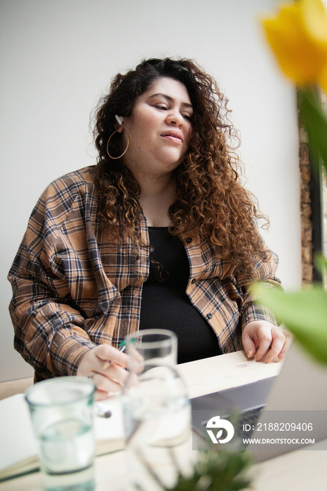 Plus-sized Sri Lankan woman with vitiligo working from home with earbuds