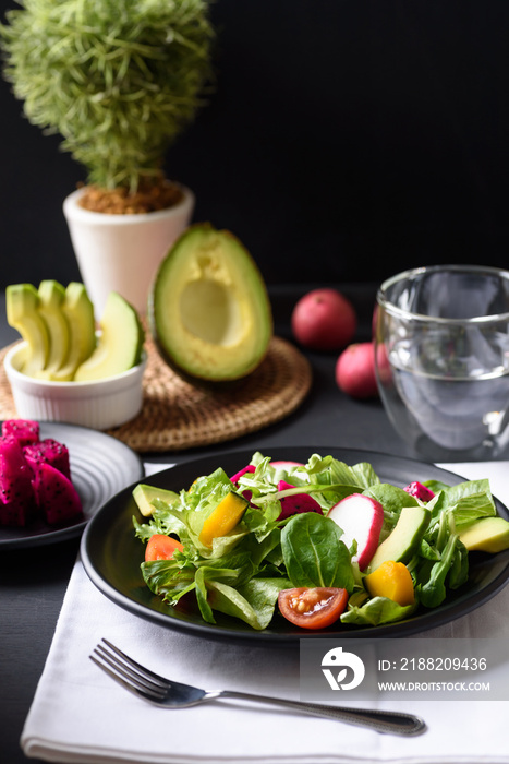 Fresh fruit and vegetable salad with avocado, dragon fruit, pumpkin, tomato, radish, lettuce and corn salad. Concepts of healthy food, vegetarian and lifestyle trends.