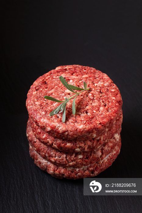 Food Concept Ground beef or hamburger beef patty stack on black slate board with copy space