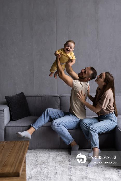 Happy young parents play have fun with excited little son in living room.