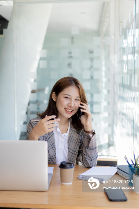 Asian woman talking on the phone, she is a salesperson in a startup company, she is calling customers to sell products and promotions. Concept of selling products through telephone channels.