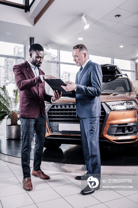 Sales manager wearing trousers and dark red jacket standing near client