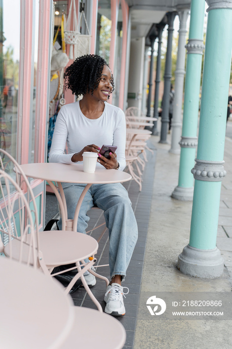 Woman using smart phone during coffee break in sidewalk cafe