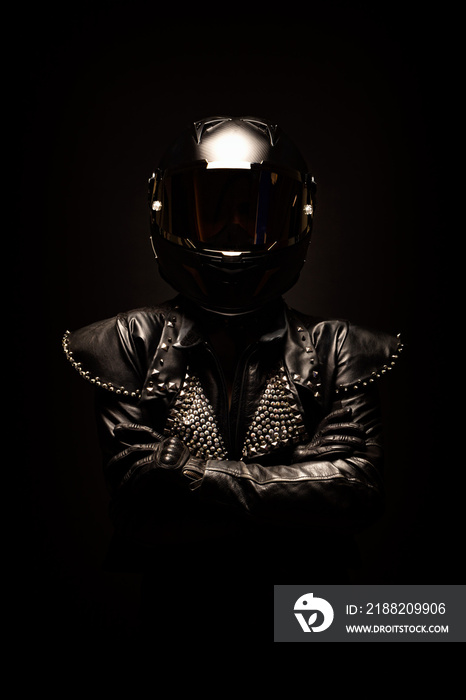 Portrait of a young female biker wearing a studded leather jacket and a black helmet