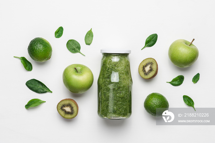 Green smoothie in glass bottle and organic vegetables and fruits. White background, top view