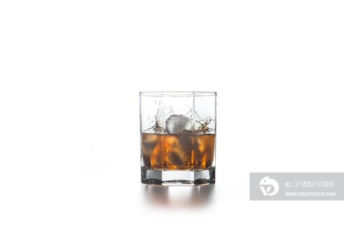 Whiskey splash from the fallen ice cube into glass with beverage on light background..