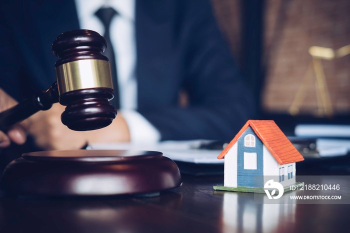 Real Estate Law concept. Gavel on sounding block in hand’s Male judge at a courtroom, working for the insurance compensations. report the case on table in modern office.