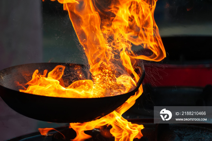 Chef cooking with fire in frying pan