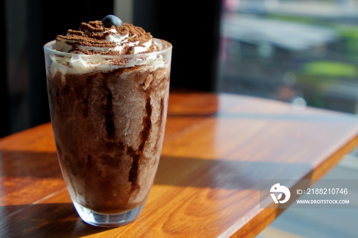 Chocolate frappe with whip cream and blueberry on wooden table in cafe.