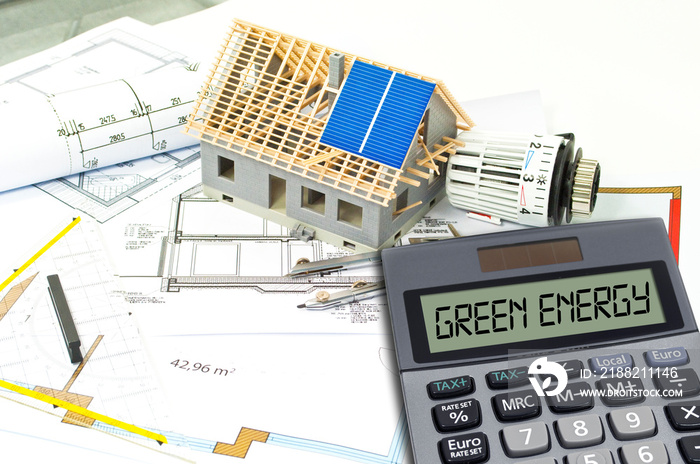 Solar energy cells on a blueprint or construction plan with calculator showing the word green energy