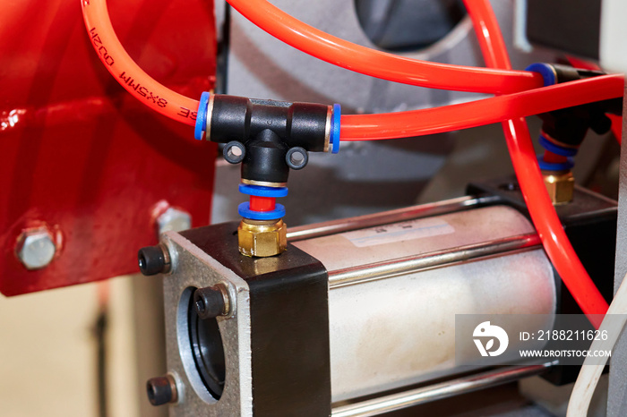 orange duct tubes of pneumatic system connected to pneumatic cylinder