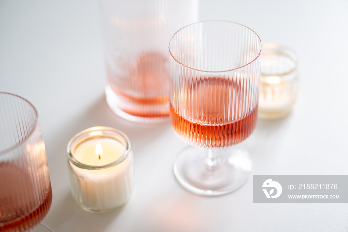 Rose wine in trendy ribbed wineglasses and decanter on white table